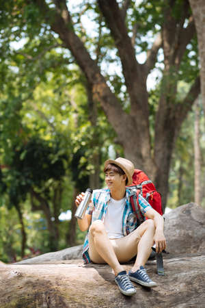 Vietnamese traveller sitting on the tree trunk and drinking teaの写真素材