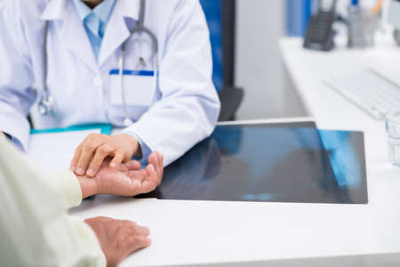 Doctor touching hand of her patient to check his pulseの写真素材