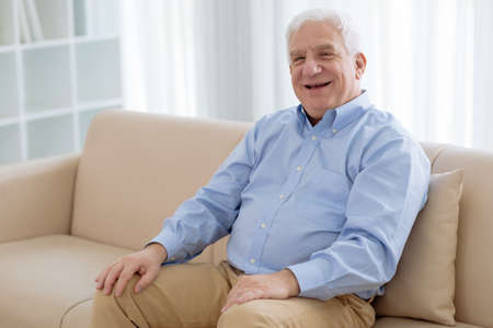 Senior man sitting at home and laughingの写真素材