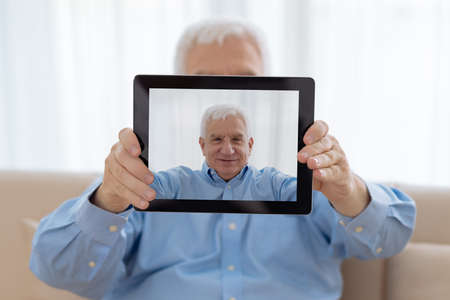Senior man taking selfie with digital tabletの写真素材