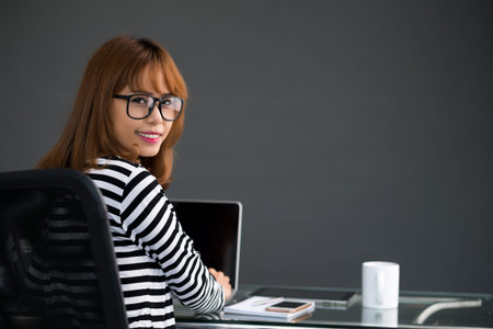 Successful businesswoman in glasses smiling and looking at cameraの写真素材