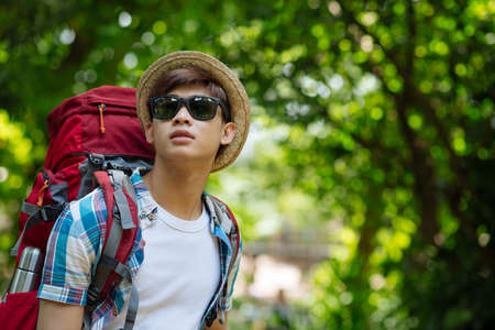 Portrait of backpacker in sunglasses standing in the forestの写真素材