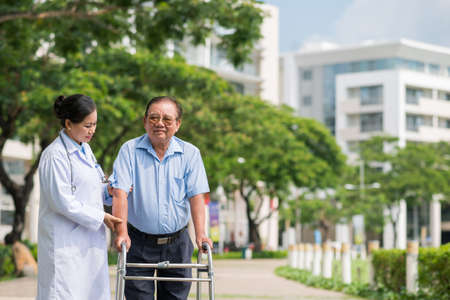 Doctor walking in park with her disabled patientの写真素材