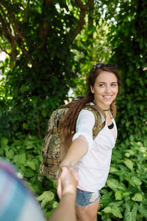 Smiling female backpacker taking helping hand of her boyfriendの写真素材