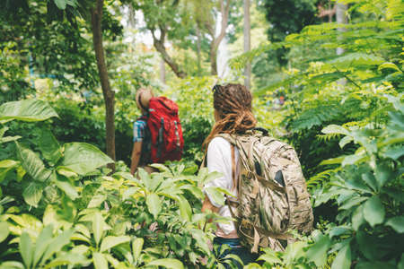 Man and woman with backpacks trekking in the forest, rear viewの写真素材
