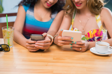 Women sitting at café and using modern technologies