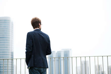 Rear view of businessman standing on balconyの写真素材