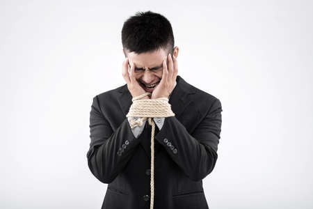Crying man with chained hands holding head in handsの写真素材