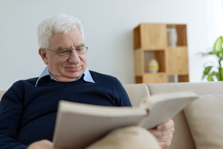 Handsome senior man reading a book at homeの写真素材