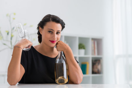 Elegant pretty woman with a bottle of white wine and two glassesの写真素材
