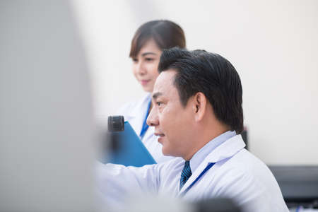 Side view of optometrist using professional equipment in medical officeの写真素材
