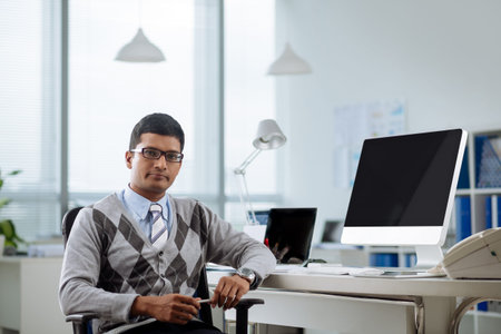 Portrait of confident Indian programmer at his workplace