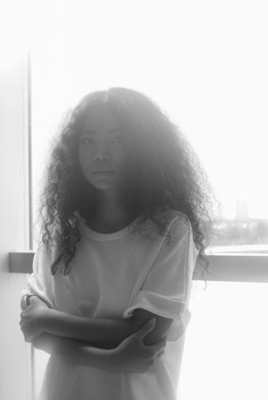 Monochrome portrait of beautiful curly girl looking at the camera, backlit