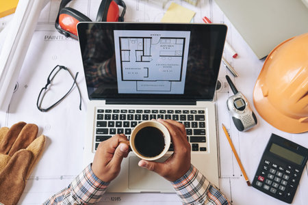 Engineert drinking coffee and examinig blueprint, view from the topの写真素材