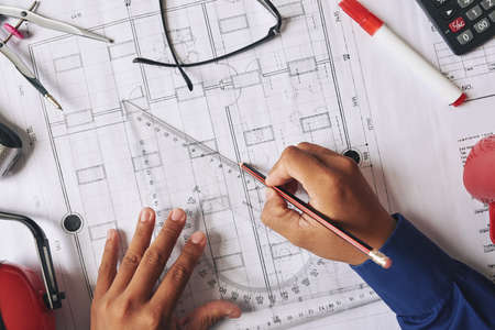 Hands of engineer using plastic triangle when drawing blueprintの写真素材