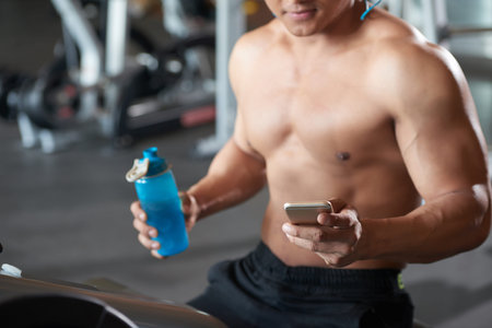 Close-up image of sportsman using smartphone in gymの写真素材