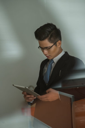 Asian businessman reading news on digital tablet