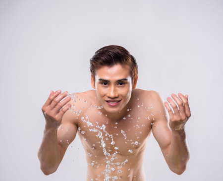 Smiling man washing his face with fresh waterの写真素材