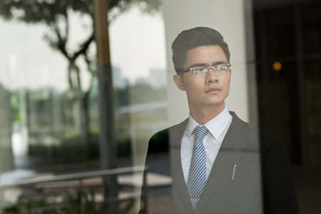 Portrait of serious Asian business executive looking in distanceの写真素材