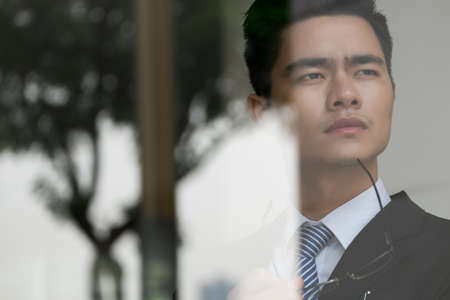 Face of pensive Asian businessman pondering over new ideaの写真素材