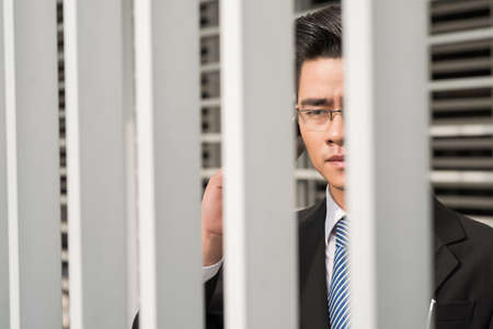 Serious businessman behind railing talking on the phoneの写真素材