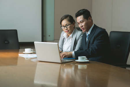 Businessman and business lady watching something together on laptopの写真素材