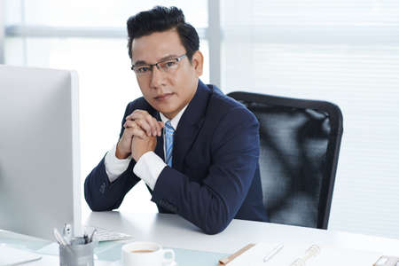 Portrait of Vietnamese entrepreneur sitting at his workplaceの写真素材