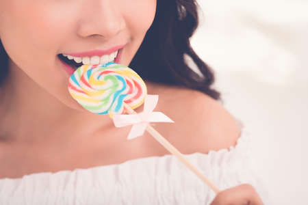 Close-up image of young woman biting lollipopの写真素材