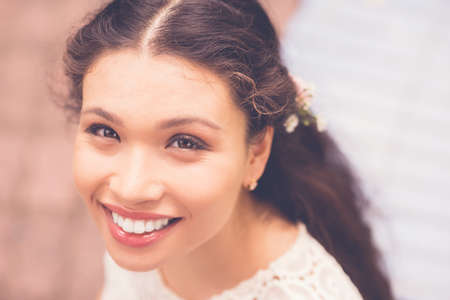 Face of young attractive mixed-race woman looking at camera and smilingの写真素材