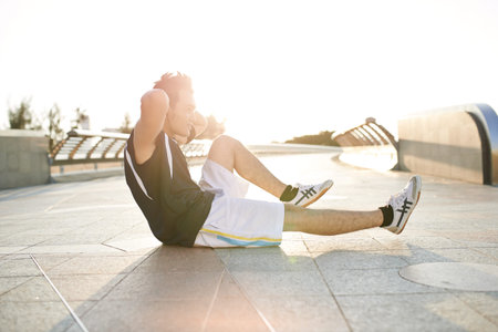 Male athlete doing exercising for abs outdoors, backlit