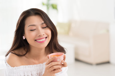 Smiling woman enjoying tea in little cupの写真素材