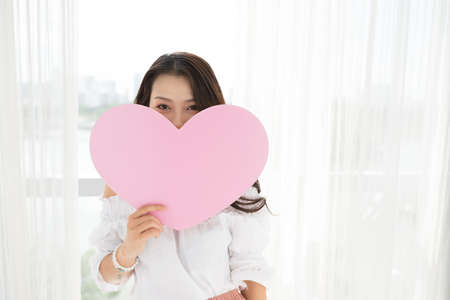 Young Vietnamese woman with pink paper heartの写真素材