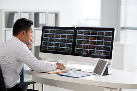 Financial analyst looking at the monitors and talking on phone