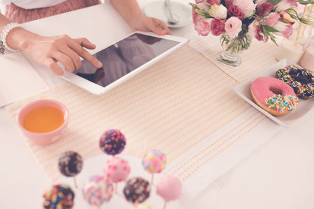 Female hands using digital table at the table with different sweets