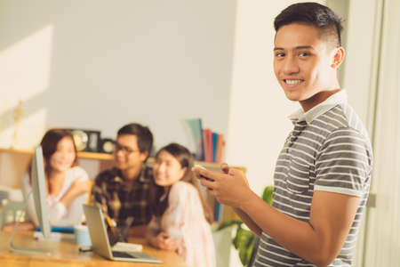 Smiling high school student with smartphone in his hands smiling at cameraの写真素材