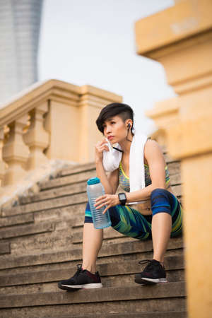 Vietnamese female jogger resting on the stepsの写真素材