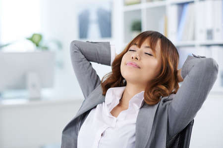 Portrait of pretty Vietnamese business lady dreaming in her chairの写真素材