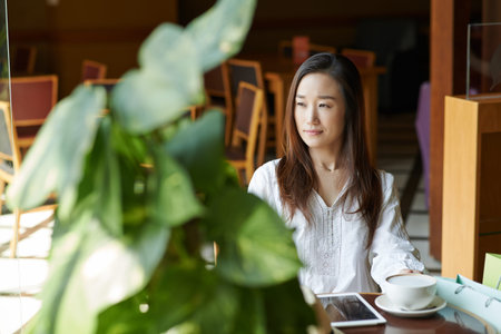 Pensive Korean woman looking at cafe window