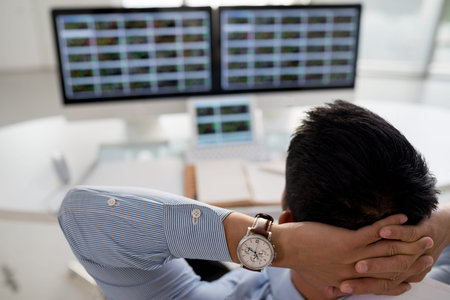Businessman sitting in front of computers and following stock exchange market
