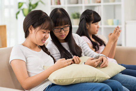 Smiling schoolgirls watching video on smartphone