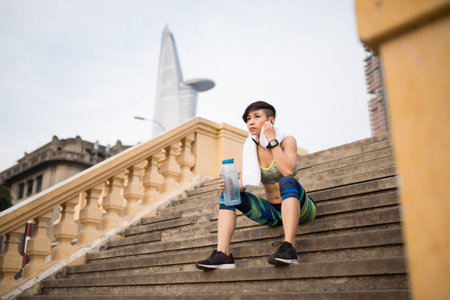 Tired sportswoman sitting on the steps after joggingの写真素材