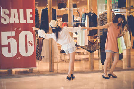 Female shopaholics going by the shop with big saleの写真素材