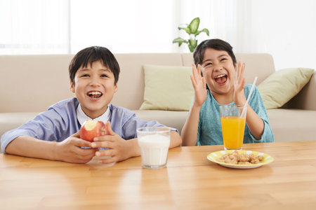 Excited children watching tv when eating breakfastの写真素材