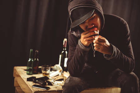 Young man in black lighting a cigaretteの写真素材