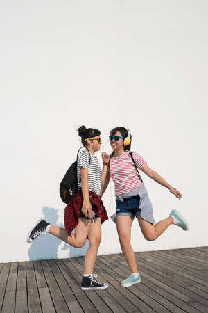 Teenage friends in headphones dancing outdoorsの写真素材