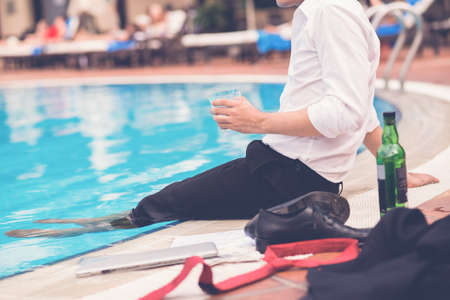 Cropped image of tired businessman drinking at swimming poolの写真素材