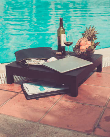 Table with business accessories, fruits and wine at the poolの写真素材