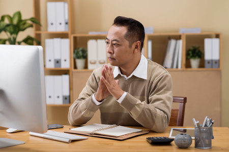 Pensive mixed-race business executive looking at computer screenの写真素材