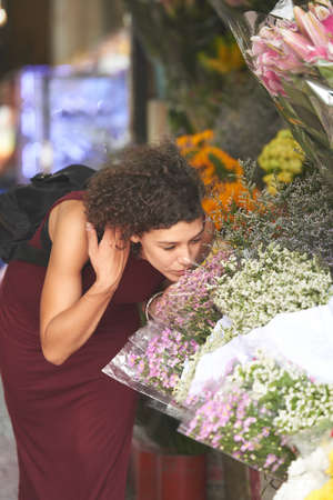 Young woman smelling beautiful flowers at marketの写真素材