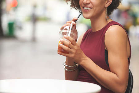 Cropped image of smiling woman enjoying tasty cocktail outdoorsの写真素材